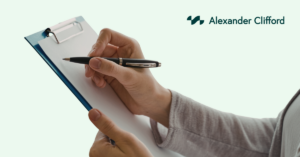 Hand holding a clipboard and pen taking notes, representing a competent professional assessing R&D tax relief claims, with Alexander Clifford logo on a light green background